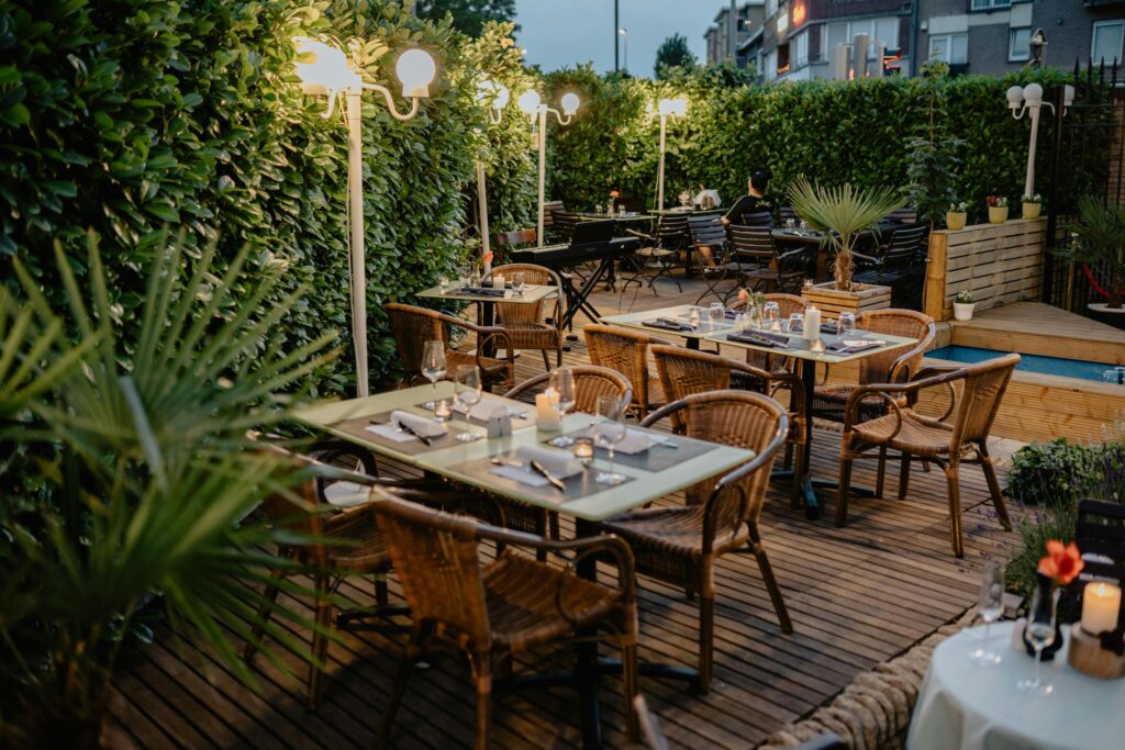 Cozy outdoor dining area with warm lighting and lush greenery, perfect for evening dinners.