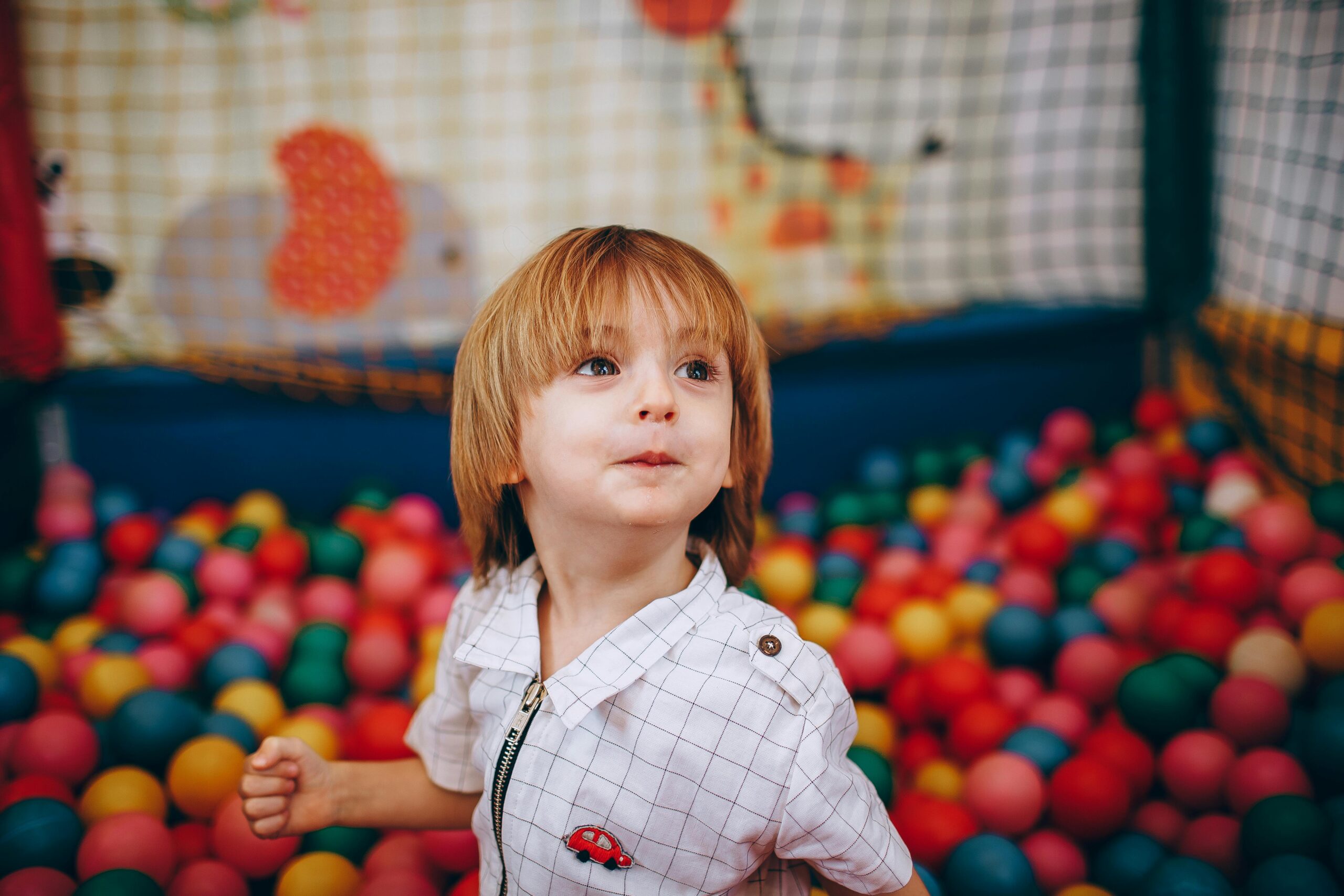 A cheerful child having fun in a colorful indoor ball pit, capturing joy and playfulness.